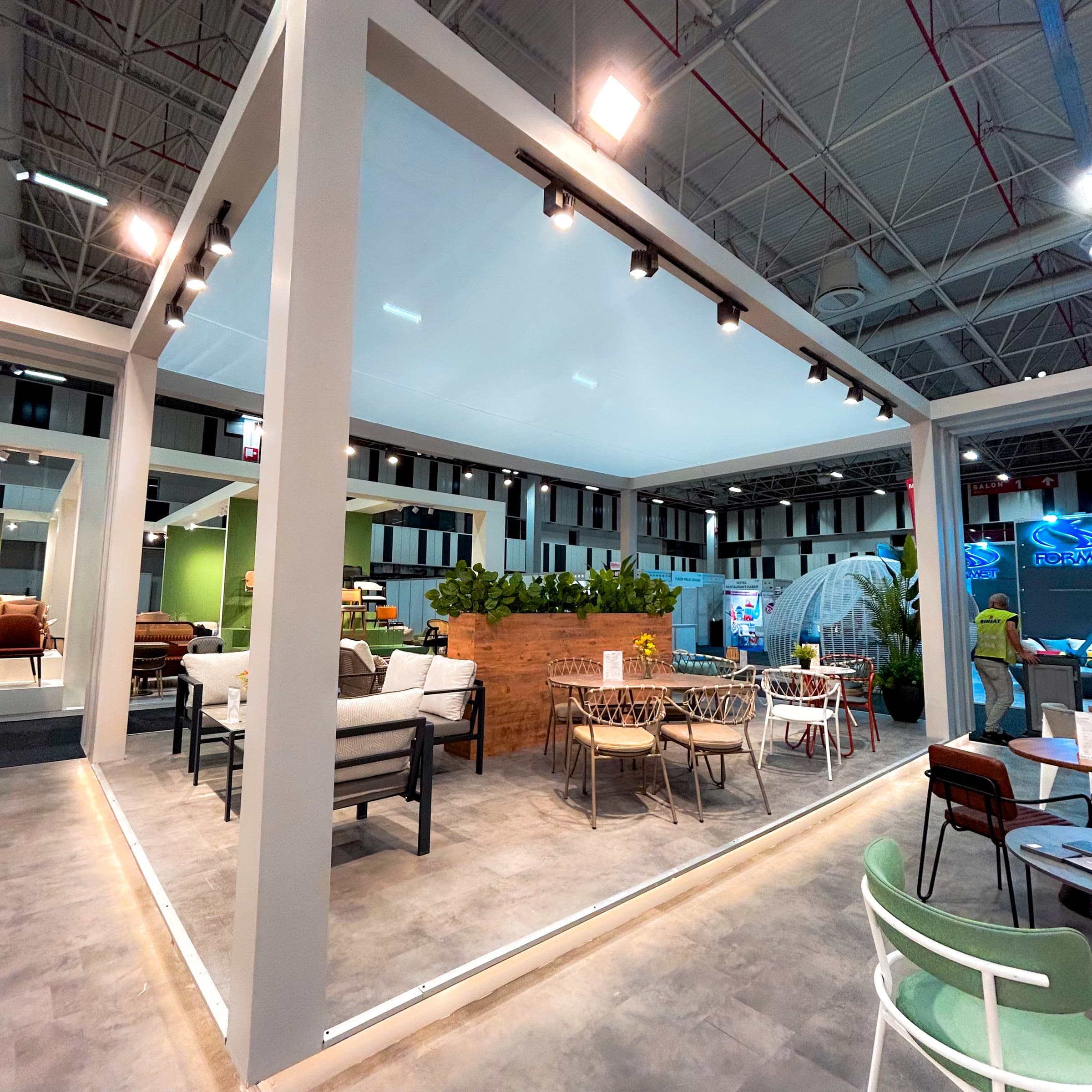 Modular exhibition stand with a white pergola frame and outdoor furniture